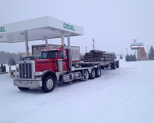 LeFebvre truck hauling commercial concrete building component in the snow at gas station.png