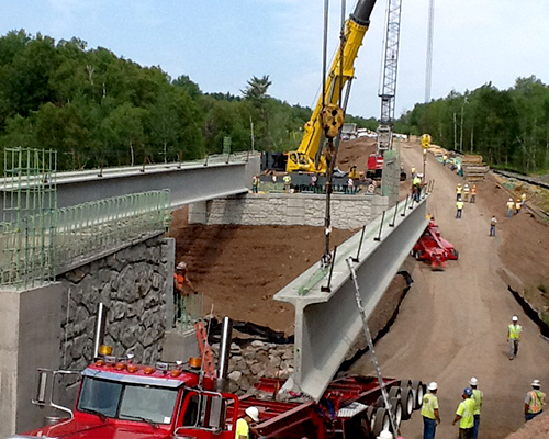 Truck unloading bridge beam at worksite.png